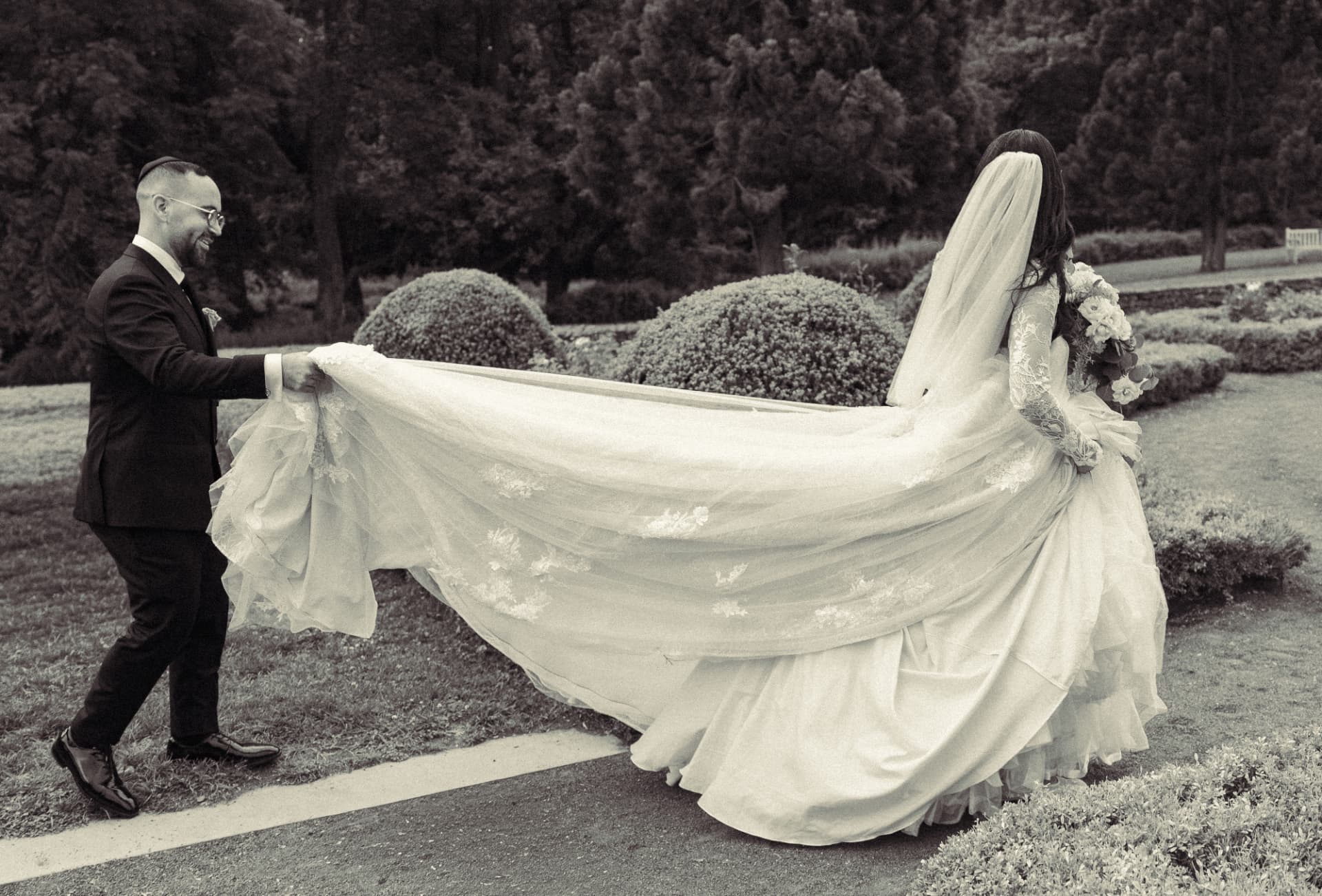 a groom carrying the trailing hem of a long dress